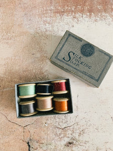 A vintage soap box filled with six vintage thread spools